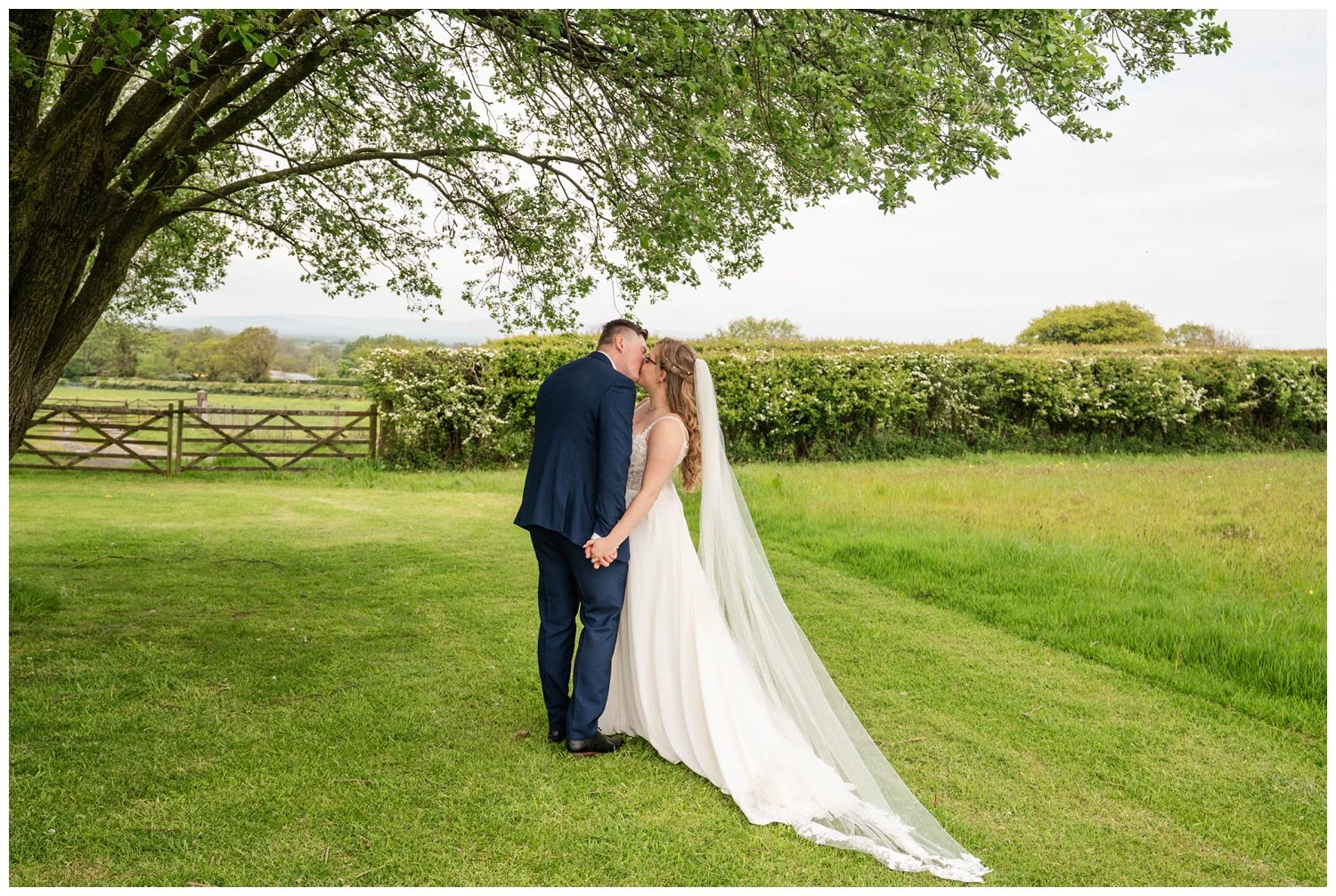 Romantic moment bride and groom kissing under a tree at Beeston Manor