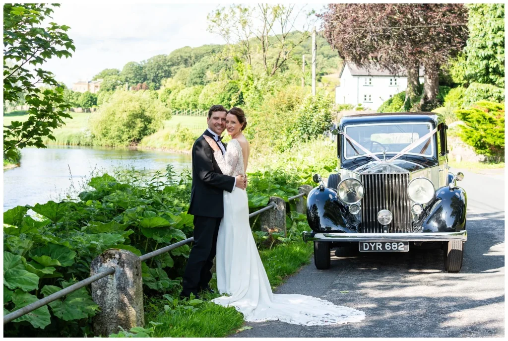 Wedding couple by a river with vintage roll royce